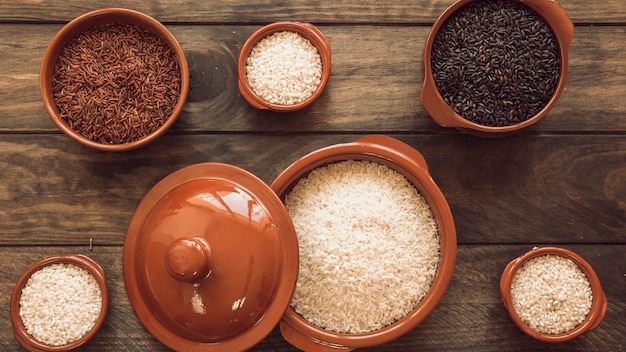 Foto gratuita tipo diferente crudo de granos de arroz en tablón de madera