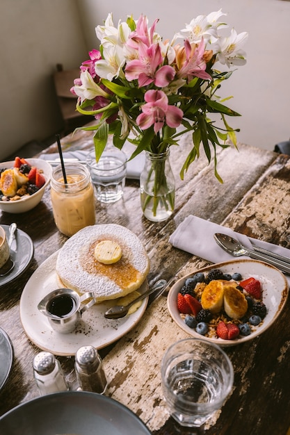 Tipos de alimentos, galletas y bebidas que se ponen en la mesa frente al florero.