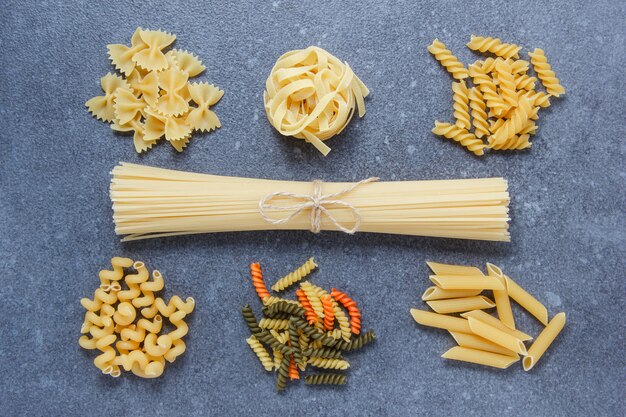 Tipos de pastas de macarrones con vista superior de espagueti sobre una superficie gris