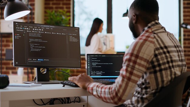 Tipos de profesionales de TI afroamericanos que programan código en monitores duales