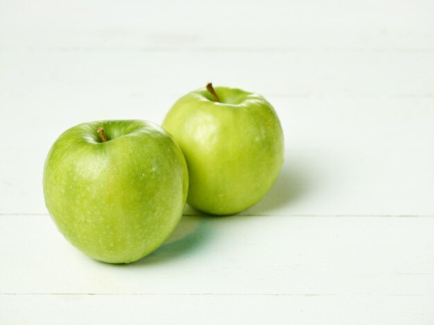 Tirado de dos manzanas verdes frescas con la hoja verde en una tabla.