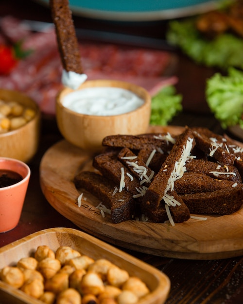 tiras de pan negro con ajo, aceite y queso rallado encima y yogurt