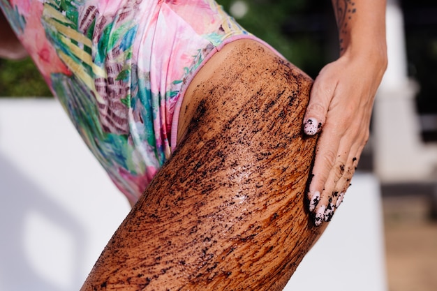 Tiro al aire libre de mujer con exfoliante corporal de café.