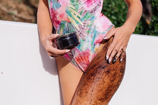 Tiro al aire libre de mujer con exfoliante corporal de café.