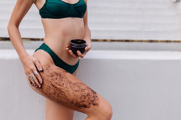 Tiro al aire libre de mujer con exfoliante corporal de café.