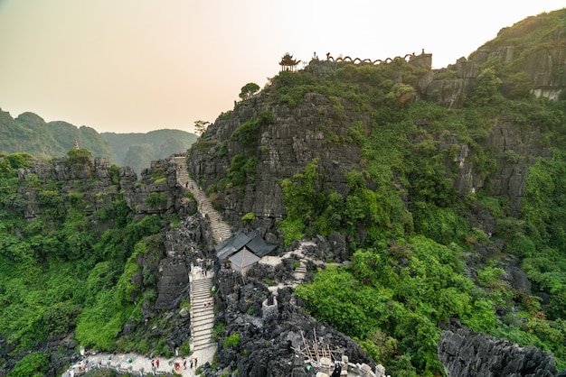 Tiro de alto ángulo de altas montañas rocosas con árboles verdes y caminos con curvas bajo el cielo despejado