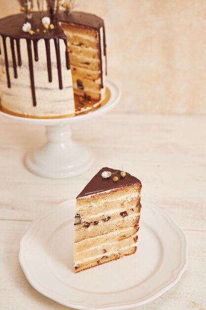 Tiro de alto ángulo de delicioso pastel Boho con goteo de chocolate y flores con adornos dorados