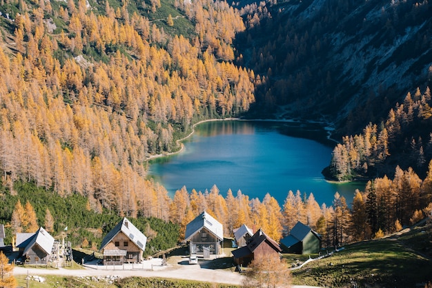 Tiro alto de un pequeño lago entre montañas con un pequeño pueblo cerca de la base de la montaña