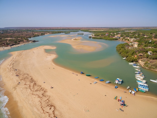 Tiro alto de playas rodeadas de cruceros y vegetación bajo un cielo azul en Senegal