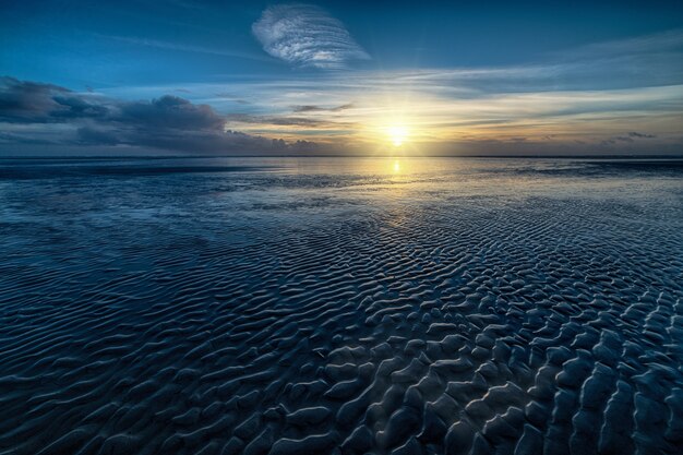 Tiro de ángulo alto del agua del océano y el sol brillando en el horizonte