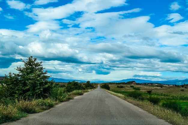 Tiro de ángulo alto de una carretera en el valle bajo el cielo con grandes nubes blancas