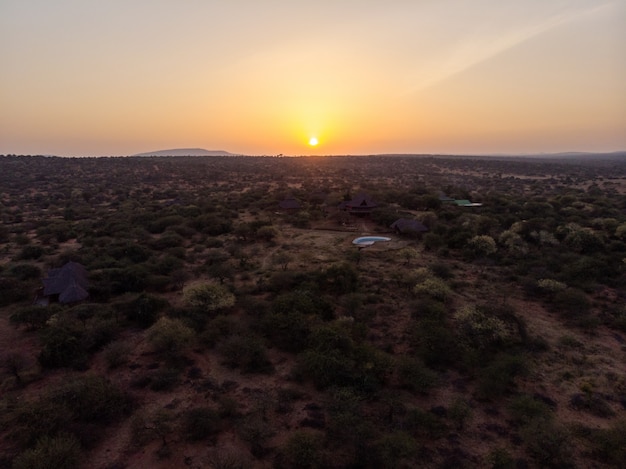 Tiro de ángulo alto de chozas entre los árboles bajo la hermosa puesta de sol capturada en Samburu, Kenia