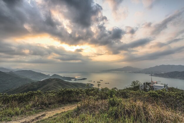 Tiro de ángulo alto de las colinas cubiertas de plantas sobre la bahía bajo el hermoso cielo nublado