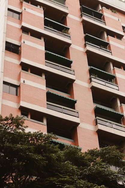 Tiro de ángulo bajo de un alto edificio de apartamentos con vegetación debajo