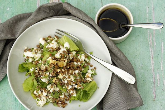 Tiro de ángulo alto de ensalada de lentejas y queso feta con aderezo balsámico y tenedor