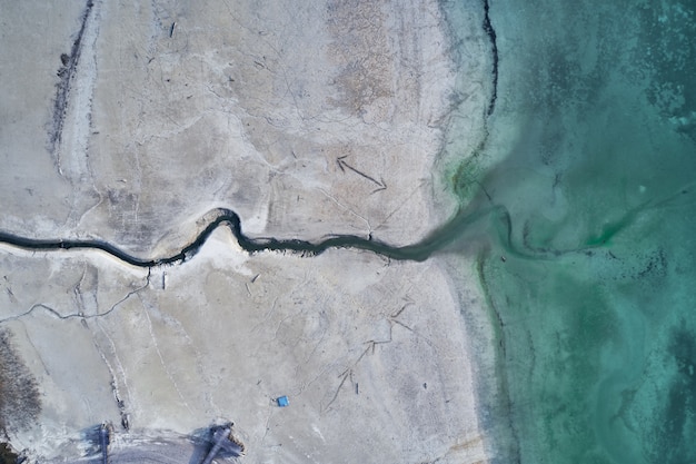 Tiro de ángulo alto de una gran grieta en la costa pedregosa junto al agua turquesa