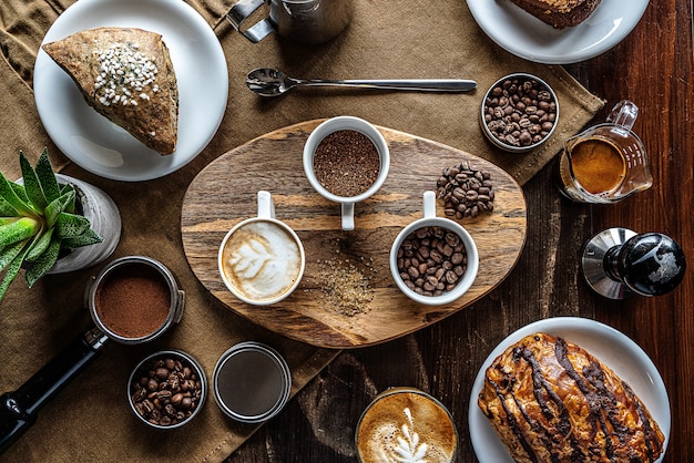 Tiro de ángulo alto de granos de café en frascos en una mesa de desayuno con algunos pasteles