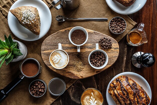 Tiro de ángulo alto de granos de café en frascos en una mesa de desayuno con algunos pasteles