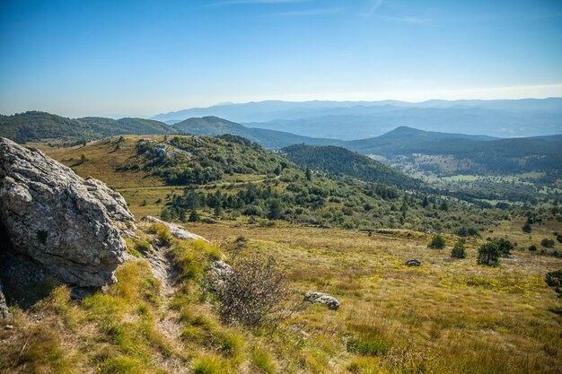 Tiro de ángulo alto de hermosas montañas con bosques bajo el cielo azul en Eslovenia