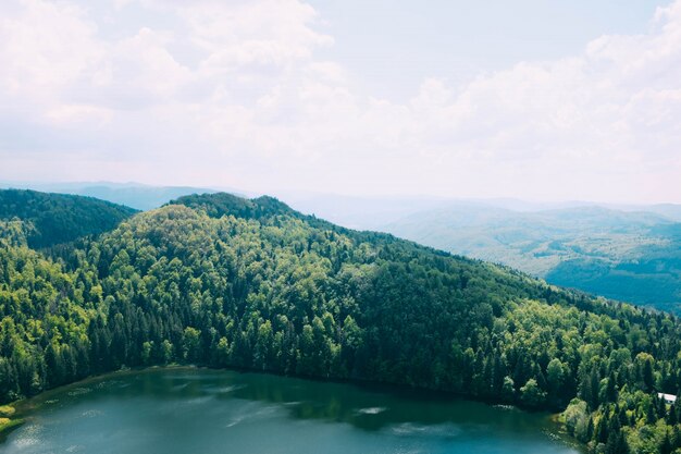 Tiro de ángulo alto de un hermoso lago rodeado de montañas cubiertas de árboles bajo el cielo nublado