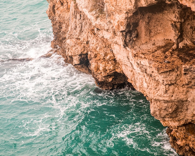 Tiro de ángulo alto de los hermosos acantilados rocosos sobre el océano capturados en Italia