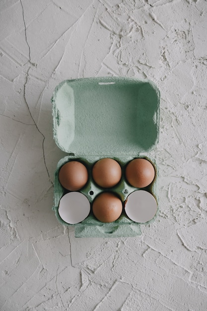 Tiro de ángulo alto de huevos y cáscaras de huevo en una caja sobre la mesa