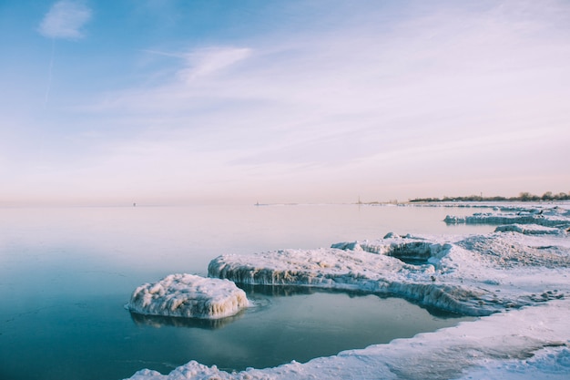 Tiro de ángulo alto de la orilla congelada del mar en invierno bajo el cielo tranquilo