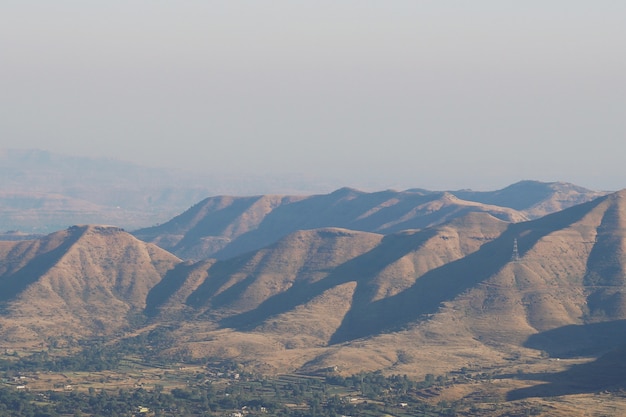 Tiro de ángulo alto del paisaje de colinas que reflejan los rayos del sol bajo el cielo despejado