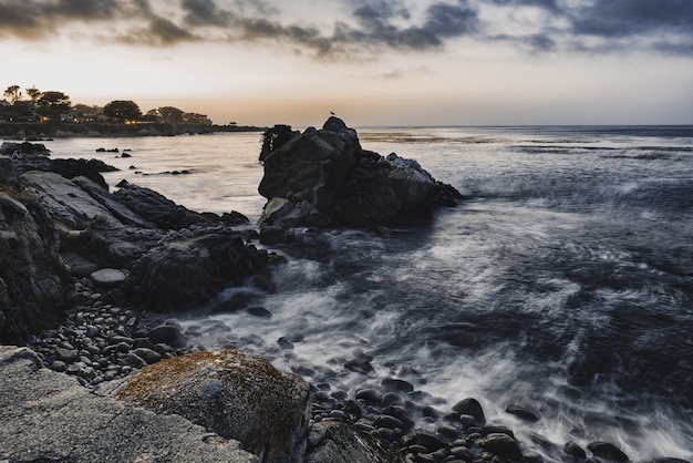 Tiro de ángulo alto de pequeñas rocas en la orilla del mar bajo el cielo nublado de la tarde