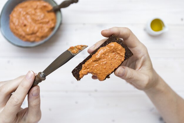 Tiro de ángulo alto de una persona que pone una deliciosa cobertura de pan tostado con un cuchillo