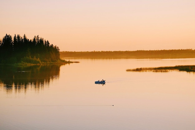 Foto gratuita tiro de ángulo alto de personas navegando en el barco en el lago durante la puesta de sol