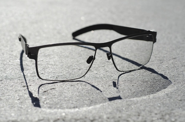 Tiro de ángulo alto de primer plano de anteojos con una sombra sobre una superficie gris