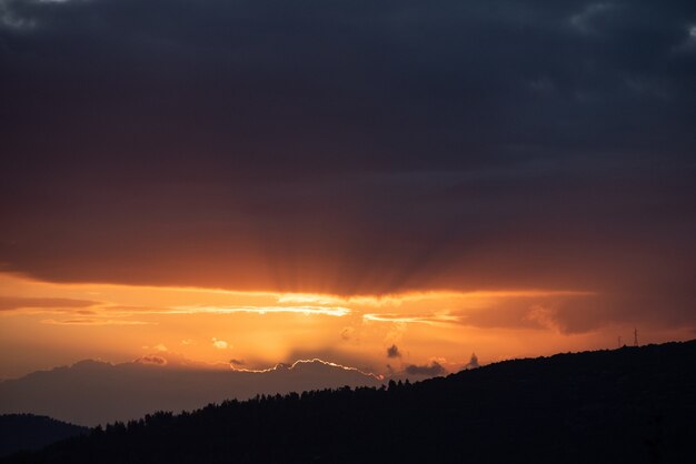 Tiro de ángulo alto de la puesta de sol en el cielo oscuro sobre las montañas