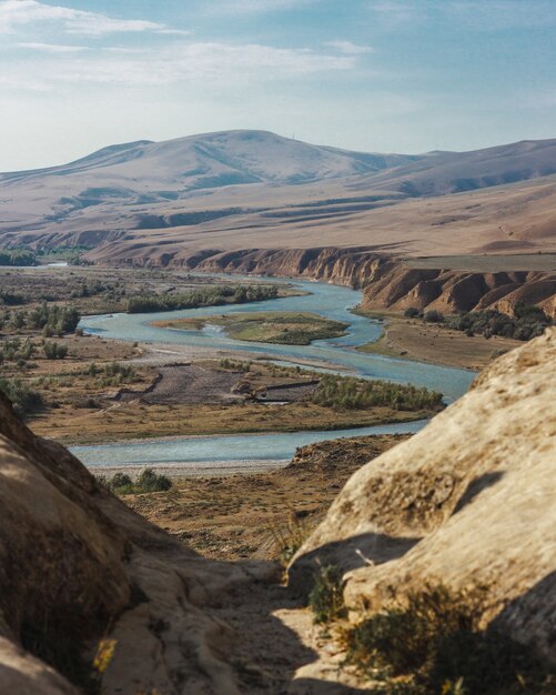 Tiro de ángulo alto de un río con curvas rodeado de altas montañas bajo el cielo nublado