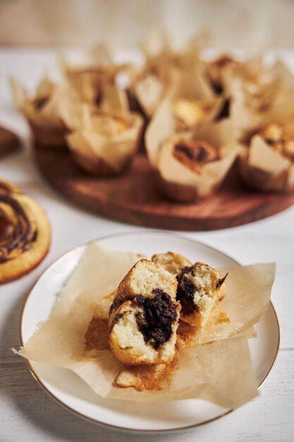 Tiro de ángulo alto vertical de un delicioso muffin de chocolate cerca de algunos muffins y donas en una mesa