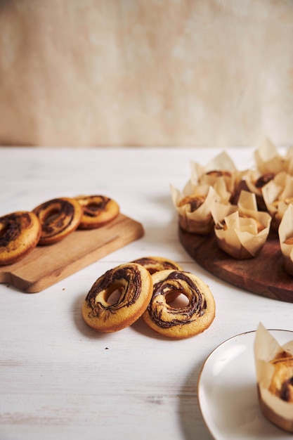 Tiro de ángulo alto vertical de deliciosos muffins de chocolate y donas sobre una mesa blanca