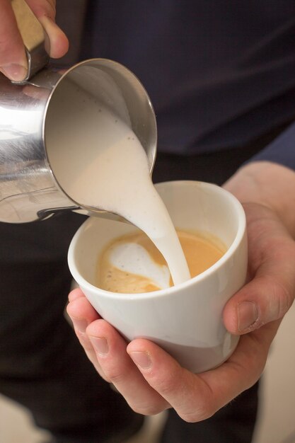 Tiro de ángulo alto vertical de un hombre haciendo una taza de capuchino