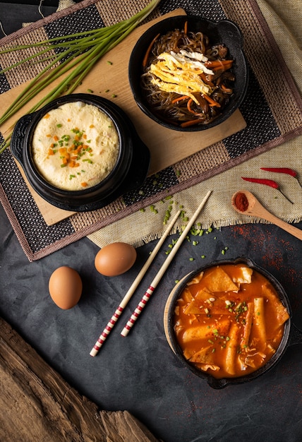 Tiro de ángulo alto vertical de tazones de hummus y sopa de verduras sobre una superficie gris