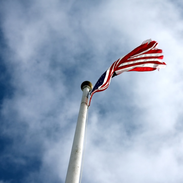 Foto gratuito tiro de ángulo bajo de una bandera de estados unidos con un cielo azul nublado