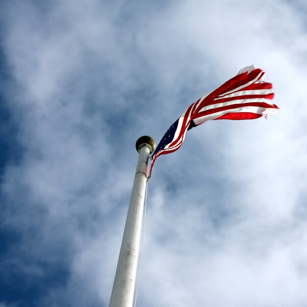 Tiro de ángulo bajo de una bandera de Estados Unidos con un cielo azul nublado