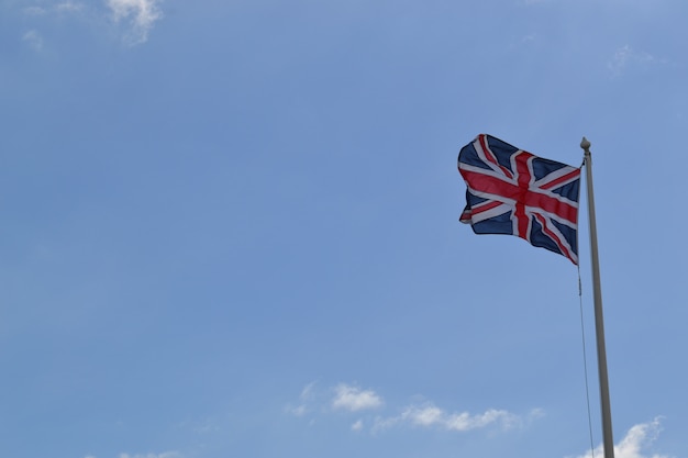 Tiro de ángulo bajo de la bandera de Gran Bretaña en un poste bajo el cielo nublado