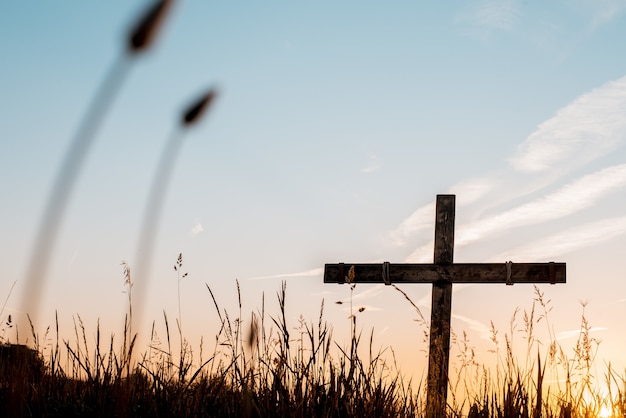 Tiro de ángulo bajo de una cruz de madera artesanal en un campo de hierba con un hermoso cielo