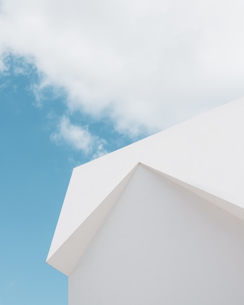 Tiro de ángulo bajo de un edificio blanco bajo una nube y un cielo azul