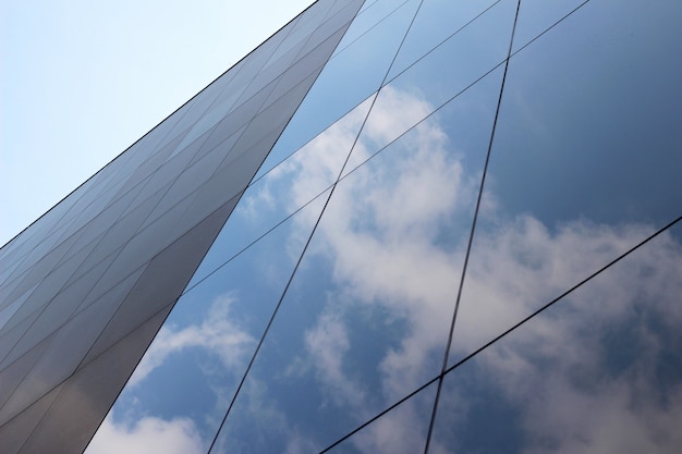 Tiro de ángulo bajo de un edificio comercial de vidrio de gran altura con un reflejo de las nubes y el cielo