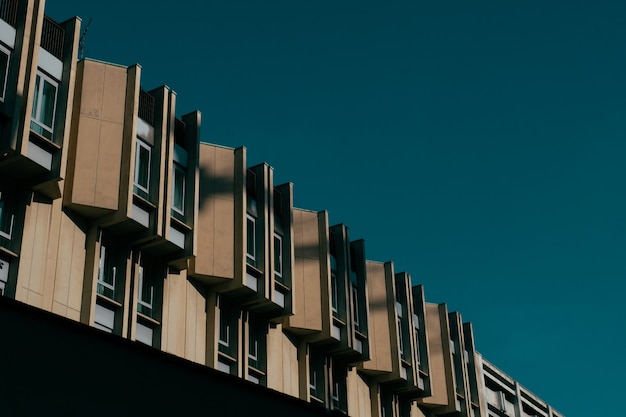 Tiro de ángulo bajo de un edificio marrón con ventanas y un cielo azul oscuro