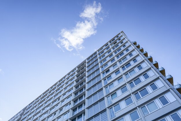 Tiro de ángulo bajo de un gran edificio bajo una nube en el hermoso cielo azul