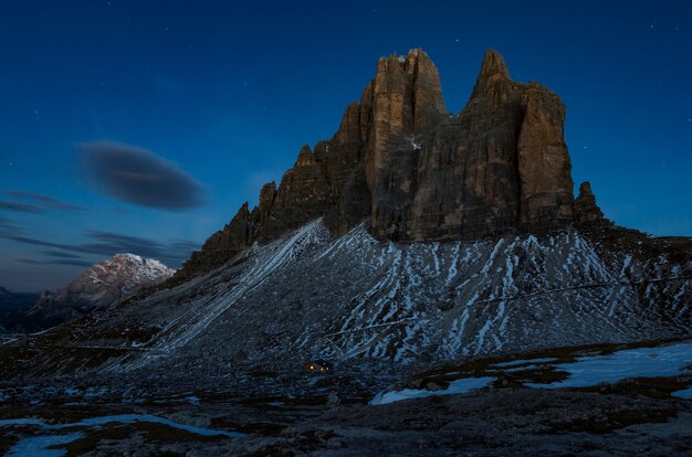 Tiro de ángulo bajo de un hermoso acantilado rocoso cubierto de nieve bajo el cielo oscuro