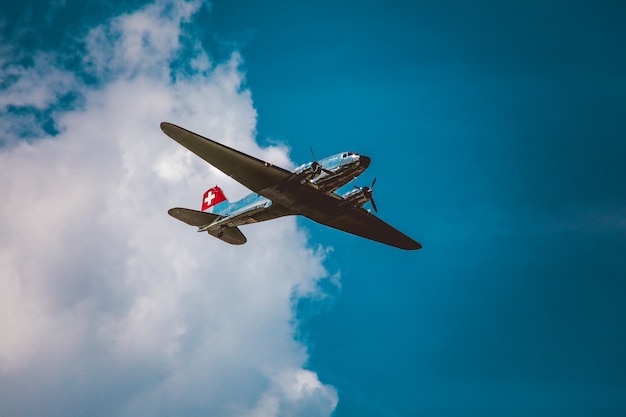 Tiro de ángulo bajo horizontal de un avión plateado bajo el hermoso cielo nublado