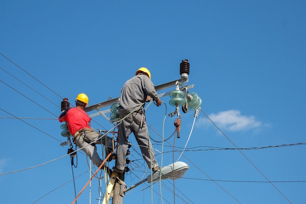 Tiro de ángulo bajo de linieros eléctricos trabajando en poste