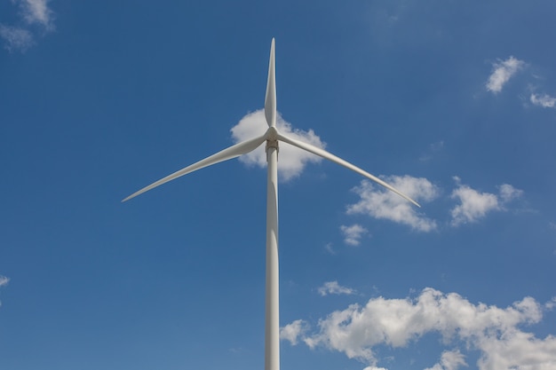 Tiro de ángulo bajo de un molino de viento bajo la luz del sol y un cielo azul durante el día - concepto ambiental